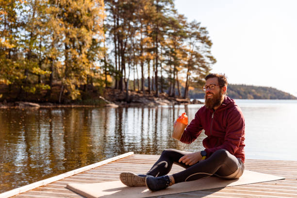 Smiling man sitting on the mat by a lake